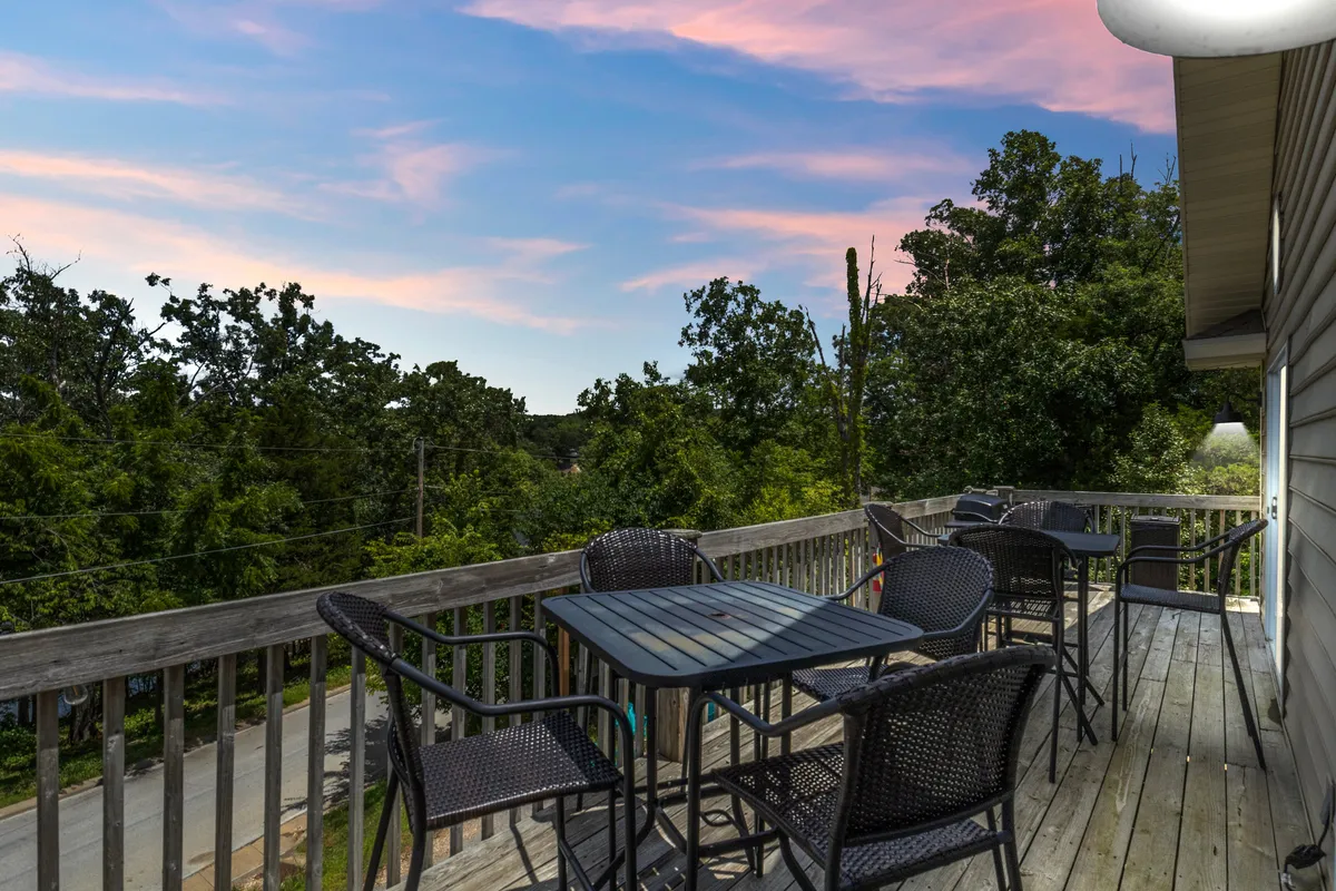An inviting outdoor seating area framed by lush greenery and a colorful evening sky. The ambiance is peaceful and serene, perfect for enjoying evening drinks, watching the sunset, or gathering with friends.