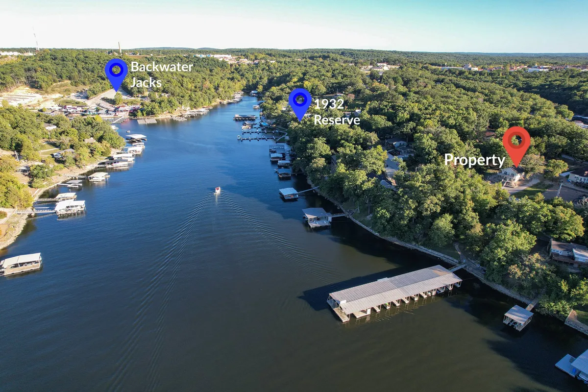 A wide view of the lake featuring a dock, lush greenery, and nearby establishments along the shore. The scene hints at community life and additional amenities close by, such as boat rentals and dining, while showcasing the expansive water ideal for boating and water sports.