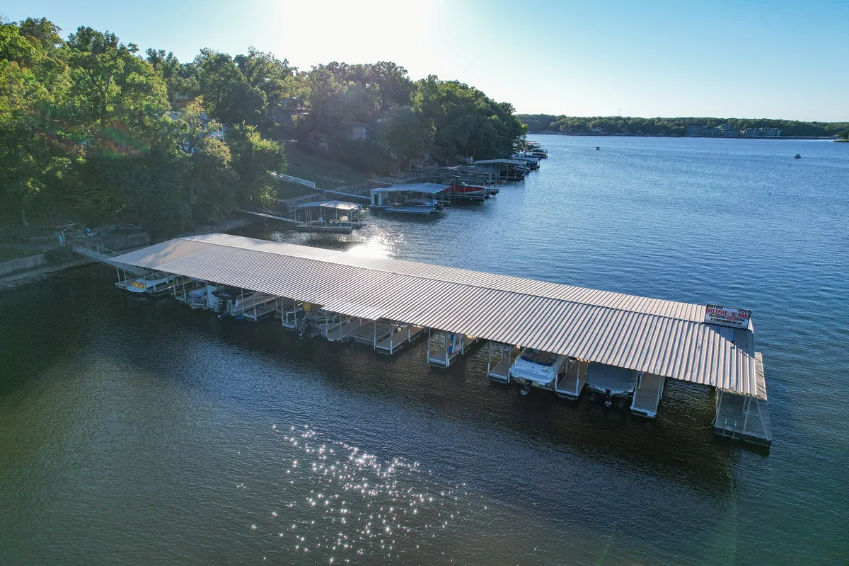 This image showcases a tranquil boathouse and dock set against calm water, with lush trees lining the shore. There is a clear view of the dock extending into the lake, inviting boating, fishing, and waterfront relaxation. The scene epitomizes direct lake access and the opportunity for a wide range of water activities.