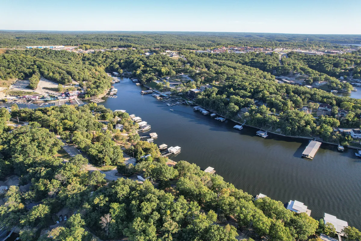 A serene lakeside view showcasing a tranquil lake, docks, greenery, and neighboring houses. The setting is perfect for both day and night activities, with water access and proximity to local hotspots.